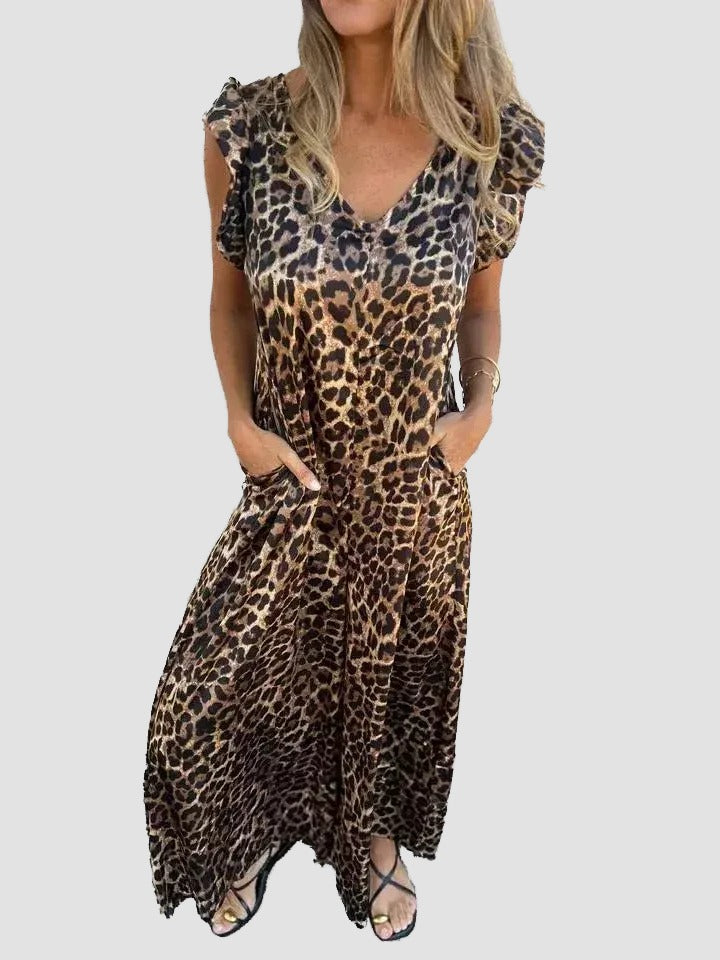 A woman wearing a leopard print dress with a v-neck and short sleeves, standing against a white background.